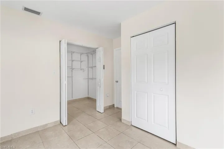 Unfurnished bedroom with light tile patterned floors and a walk in closet