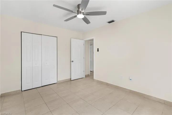 Unfurnished bedroom with light tile patterned floors, a closet, and a ceiling fan