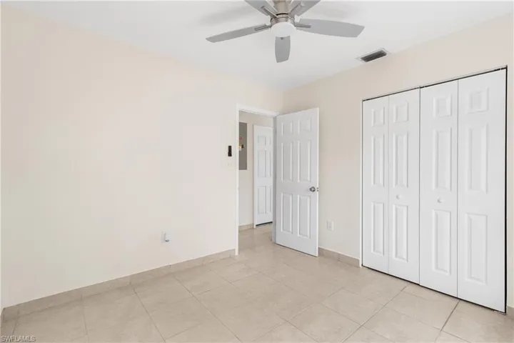 Unfurnished bedroom with light tile patterned floors, a closet, and a ceiling fan