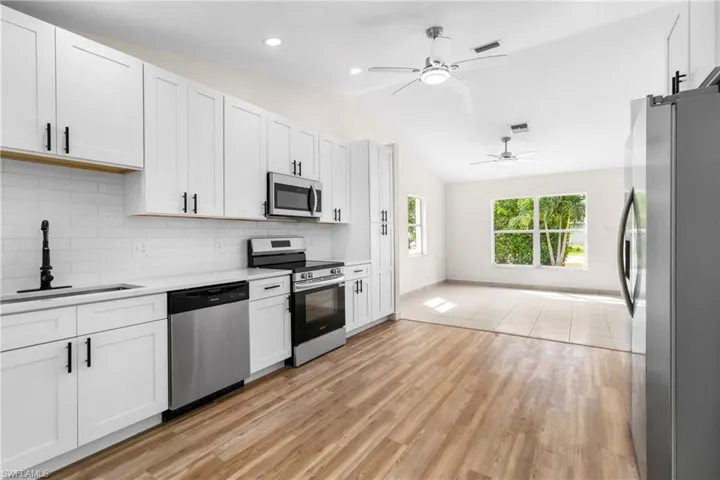 Kitchen featuring appliances with stainless steel finishes, light countertops, backsplash, a barn door, and white cabinetry