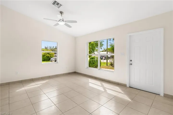 Unfurnished room with lofted ceiling, light tile patterned flooring, and a ceiling fan