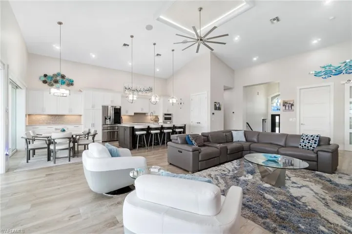 Great room with a wealth of natural light, a towering ceiling, and light wood-style plank floors