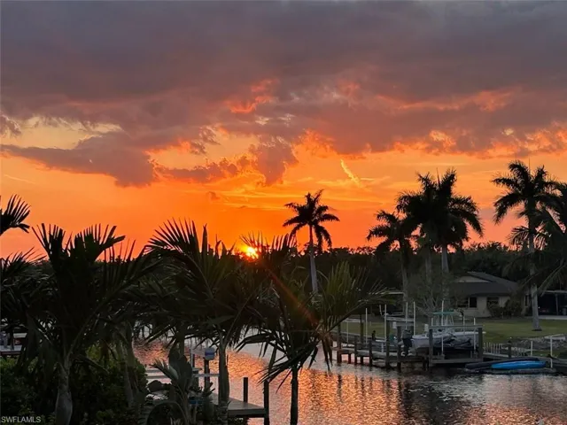 Sunset view of water feature featuring a dock