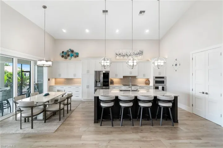 Kitchen featuring decorative light fixtures, a kitchen island with sink, and stainless steel appliances
