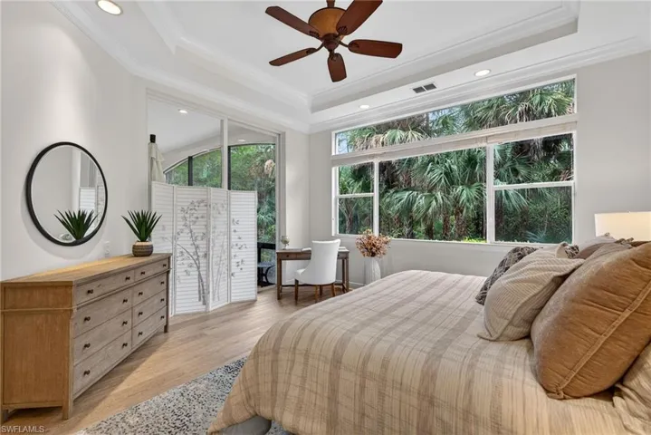 Bedroom featuring light wood-style flooring, ceiling fan, recessed lighting, ornamental molding, and a tray ceiling