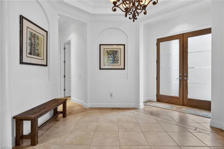 Entryway with french doors, crown molding, light tile patterned floors, and inlaid floor details