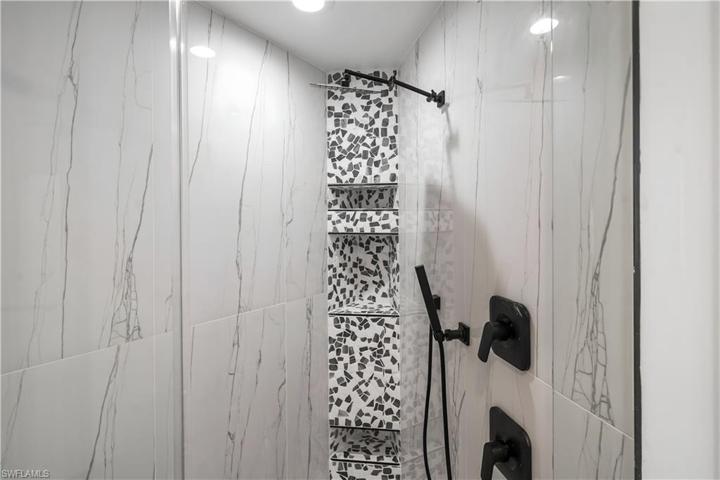 Walk in shower in master ensuite bath has floor to ceiling tile with a custom listello.Rain showerhead, hand held wand.