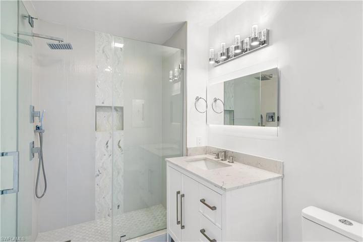 Remodeled 2nd bath has a custom listello seamless shower door. Single quartz vanity.