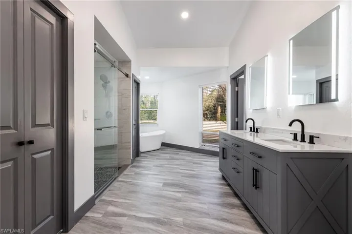 Full bathroom featuring double vanity, a freestanding bath, a stall shower, and recessed lighting