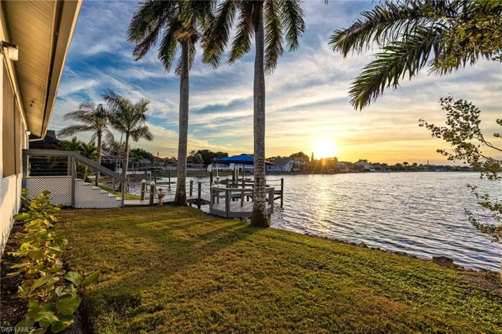 Dock with boat lift, a lawn, and a water view