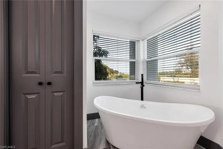 Bathroom featuring a soaking tub and a closet