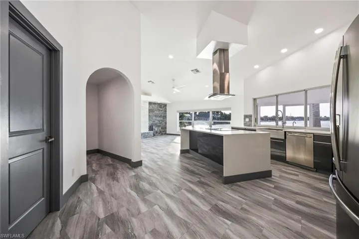 Kitchen with modern cabinets, stainless steel appliances, high vaulted ceiling, arched walkways, and open floor plan