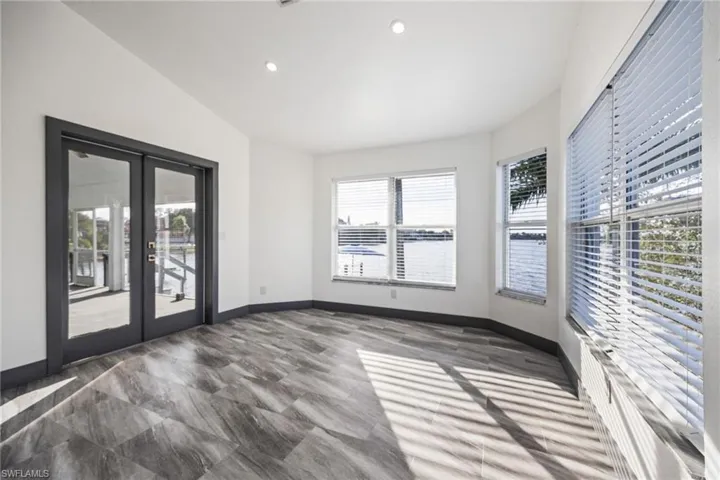 Empty room with french doors, healthy amount of natural light, recessed lighting, and lofted ceiling