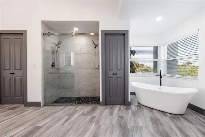 Bathroom with a closet, a soaking tub, and a shower stall
