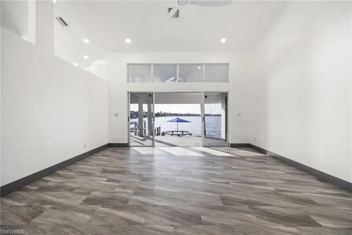 Unfurnished living room featuring a towering ceiling, recessed lighting, and a ceiling fan