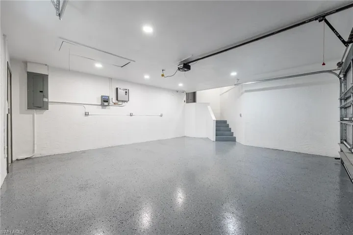 Garage featuring electric panel, a textured wall, and recessed lighting