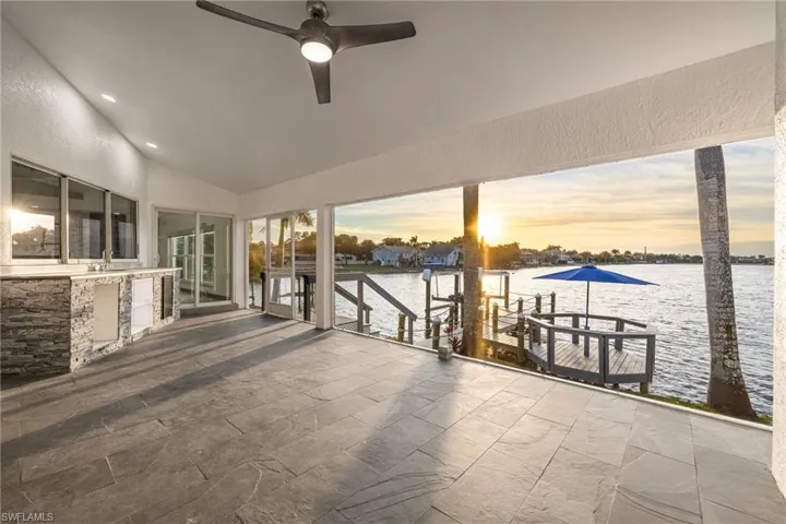 Patio terrace at dusk with a boat dock, a ceiling fan, boat lift, a water view, and a patio