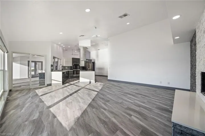 Unfurnished living room with vaulted ceiling, a fireplace, and recessed lighting