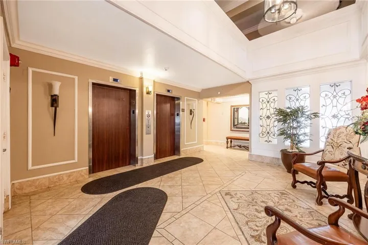 Tiled entryway with elevator and crown molding