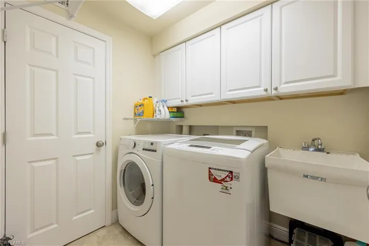 Laundry room featuring cabinets, washing machine and dryer, and sink