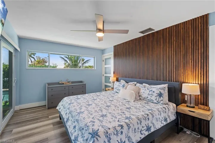 Bedroom with visible vents, baseboards, wood finished floors, and ceiling fan  - Virtually Edited Image