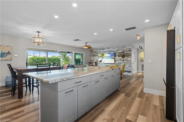 Kitchen featuring freestanding refrigerator, baseboards, gray cabinetry, a kitchen island, and recessed lighting  - Virtually Edited Image