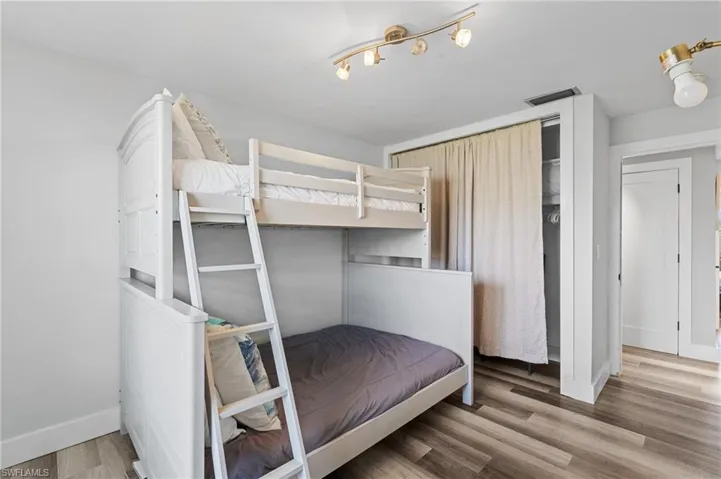 Bedroom with baseboards, wood finished floors, and visible vents  - Virtually Edited Image