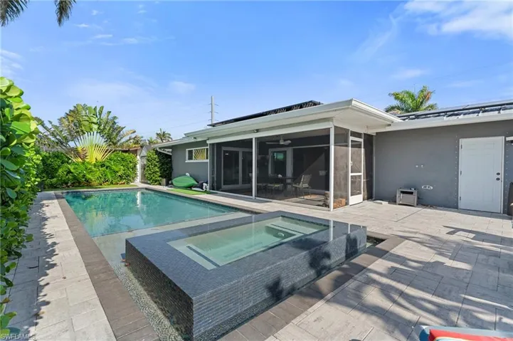 Pool featuring a patio area, a sunroom, and an in ground hot tub  - Virtually Edited Image
