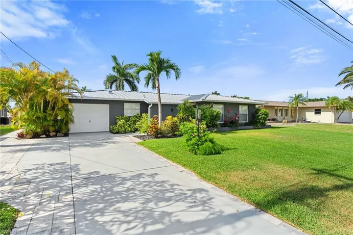 Ranch-style home with concrete driveway, an attached garage, a front yard, metal roof, and stucco siding  - Virtually Edited Image