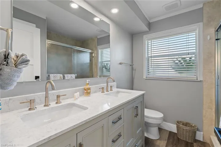 Bathroom with toilet, a sink, double vanity, and a stall shower  - Virtually Edited Image