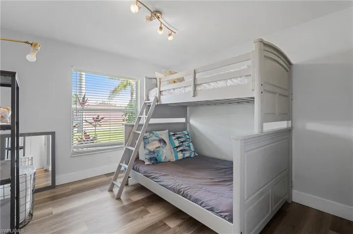 Bedroom with wood finished floors and baseboards  - Virtually Edited Image