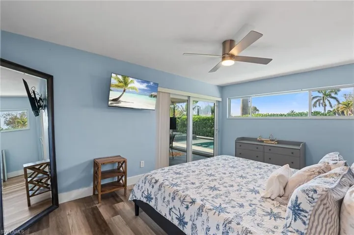 Bedroom featuring a ceiling fan, baseboards, access to outside, and dark wood-style flooring  - Virtually Edited Image