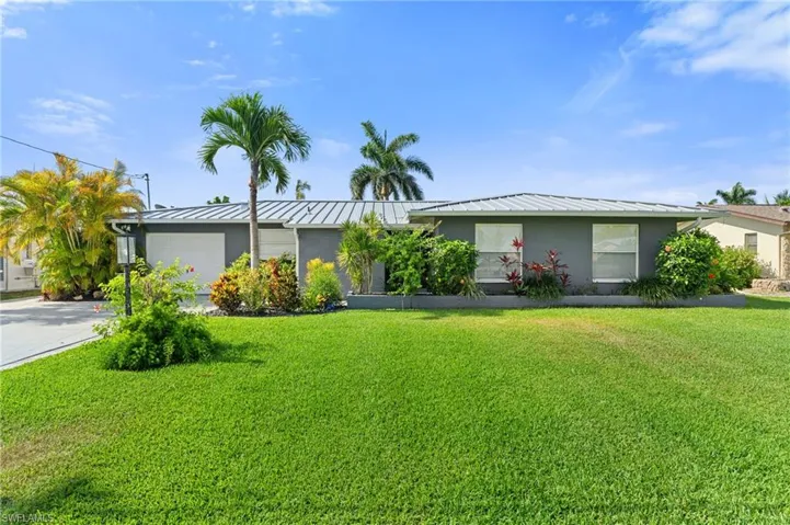 Ranch-style house featuring a garage, a front lawn, a standing seam roof, and metal roof  - Virtually Edited Image