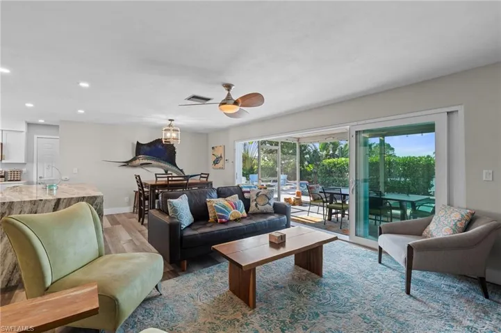 Living area featuring light wood finished floors, baseboards, visible vents, recessed lighting, and a ceiling fan  - Virtually Edited Image