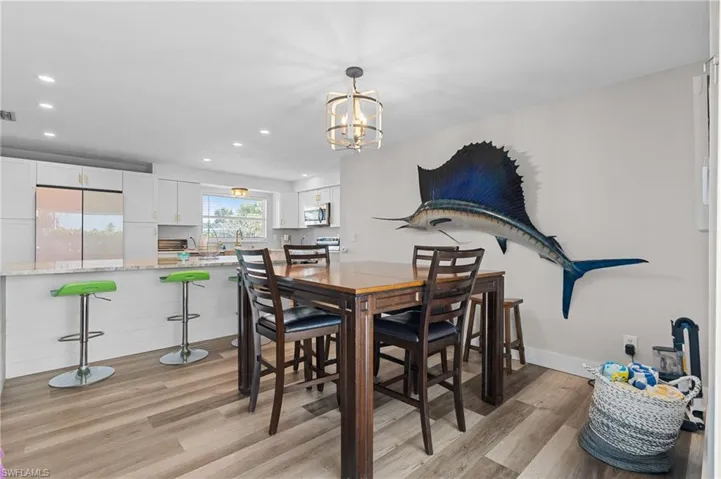 Dining room with an inviting chandelier, visible vents, recessed lighting, and light wood-style floors  - Virtually Edited Image