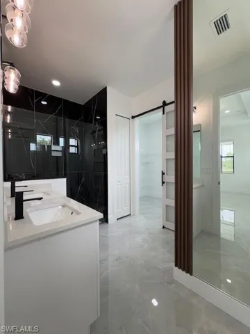 Luxury master Bathroom featuring marble tiled floors, double vanity, a marble finish shower, and recessed lighting and huge walking closet with barn door & picture's window,