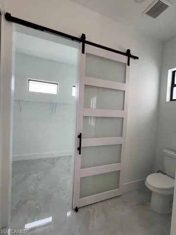 Master Bathroom featuring marble look tile flooring and a spacious closet
