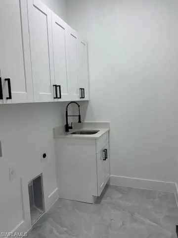 Washroom with hookup for an electric dryer, cabinet space, and light marble finish floors