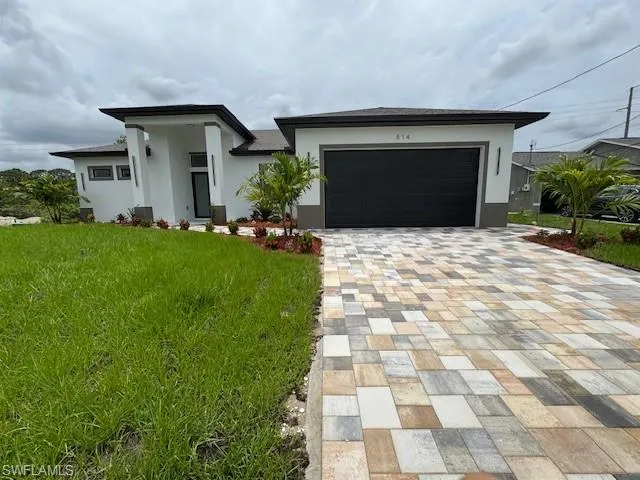 Prairie-style home with decorative driveway, stucco siding, a front yard, and a garage