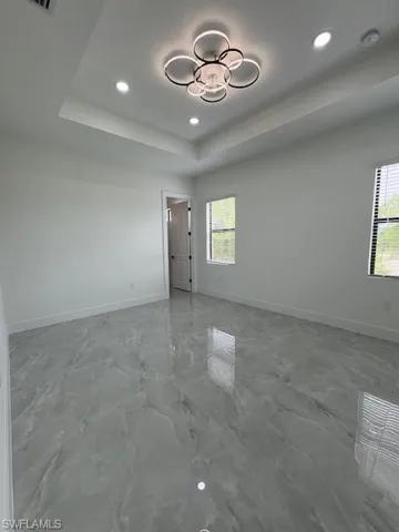Spare room featuring recessed lighting, marble finish floors, and a tray ceiling