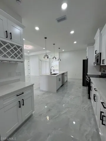 Kitchen featuring stove, recessed lighting, a center island with sink, hanging light fixtures, and light countertops