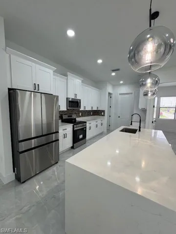 Kitchen featuring refrigerator, range, white cabinets, recessed lighting, and tasteful backsplash