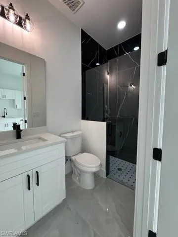 Mother - in - low's- Full bathroom with vanity, a marble finish shower, marble finish floors, and recessed lighting