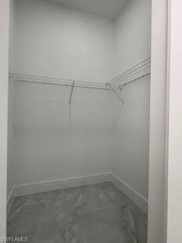 Spacious closet featuring dark marble finish flooring