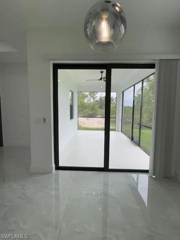 Dining room featuring marble tiled flooring and a ceiling fan and full view of the back porch with screen.