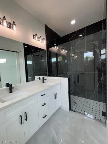 Full master bathroom with double vanity, marble tiled flooring, a marble finish shower, and recessed lighting