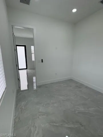 Full view from the  bedroom towards the exit door, room featuring baseboards and recessed lighting.