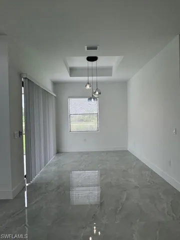 Spare room featuring a tray ceiling and baseboards