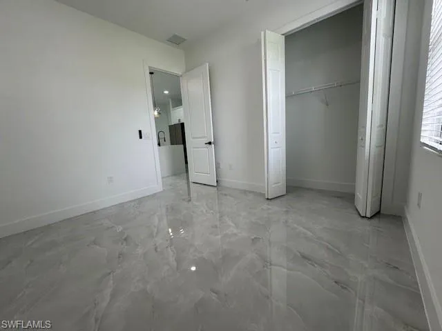 1- bed - Unfurnished bedroom featuring a closet and light marble finish flooring