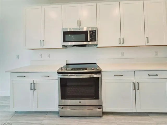 Kitchen featuring appliances with stainless steel finishes, light countertops, and white cabinets